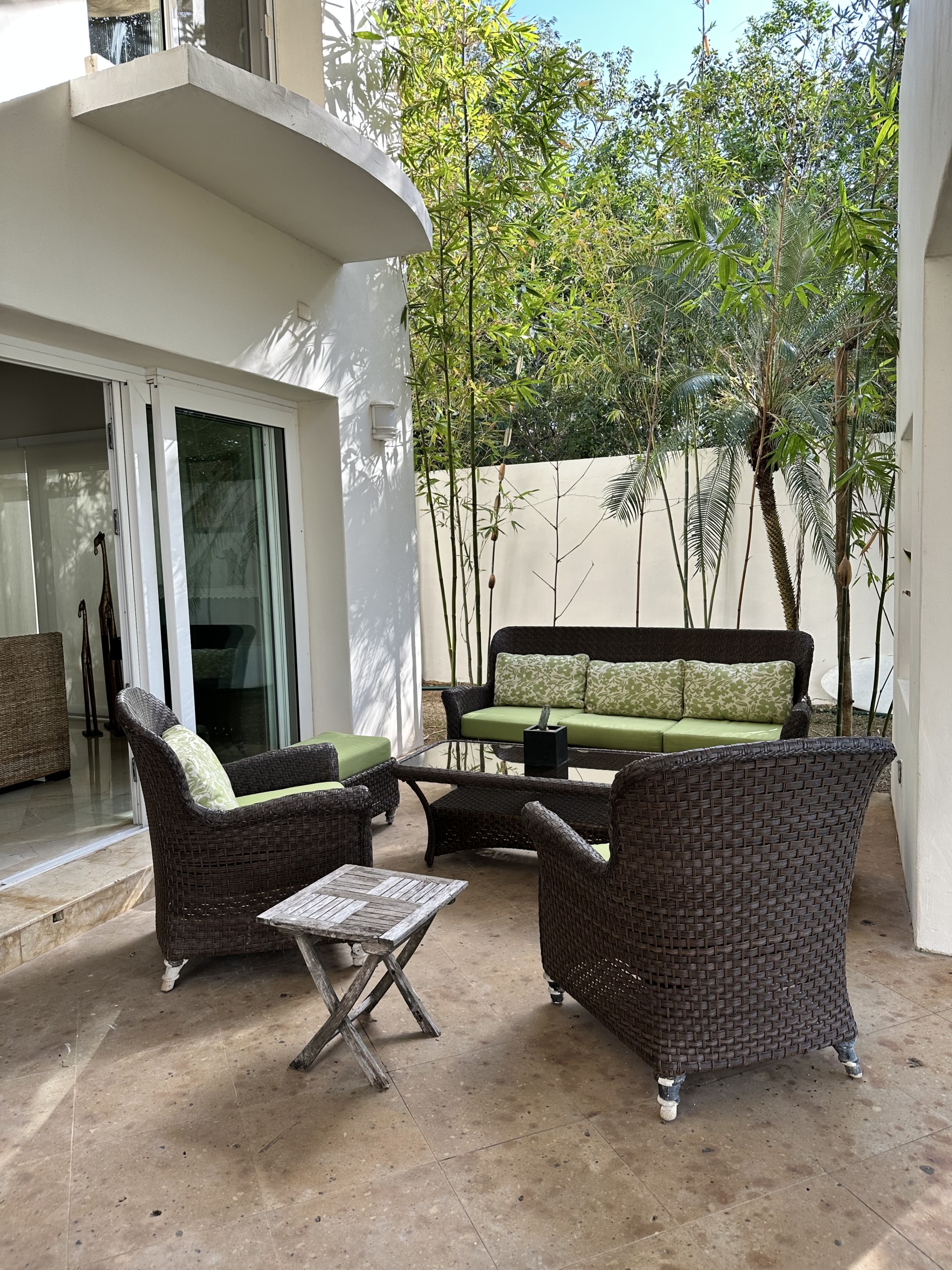 Casa en venta en lagos del sol cancun - Acogedor espacio en el exterior con muebles de mimbre oscuro rodeado de palmeras