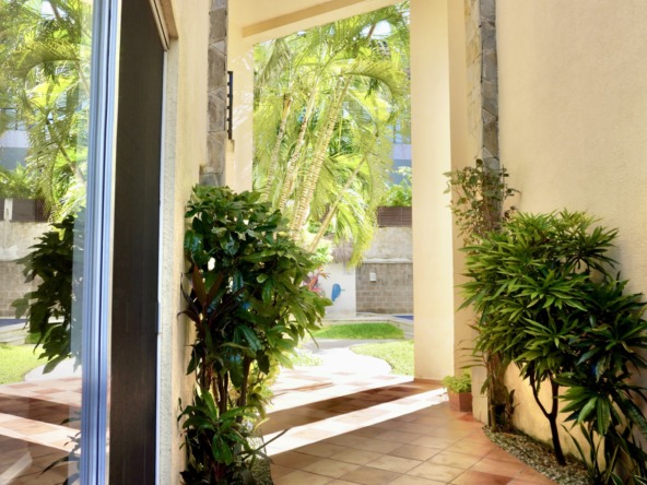 Departamento en venta en centro cancún - Entrada exterior con vegetación y vista a un jardín tropical con palmeras