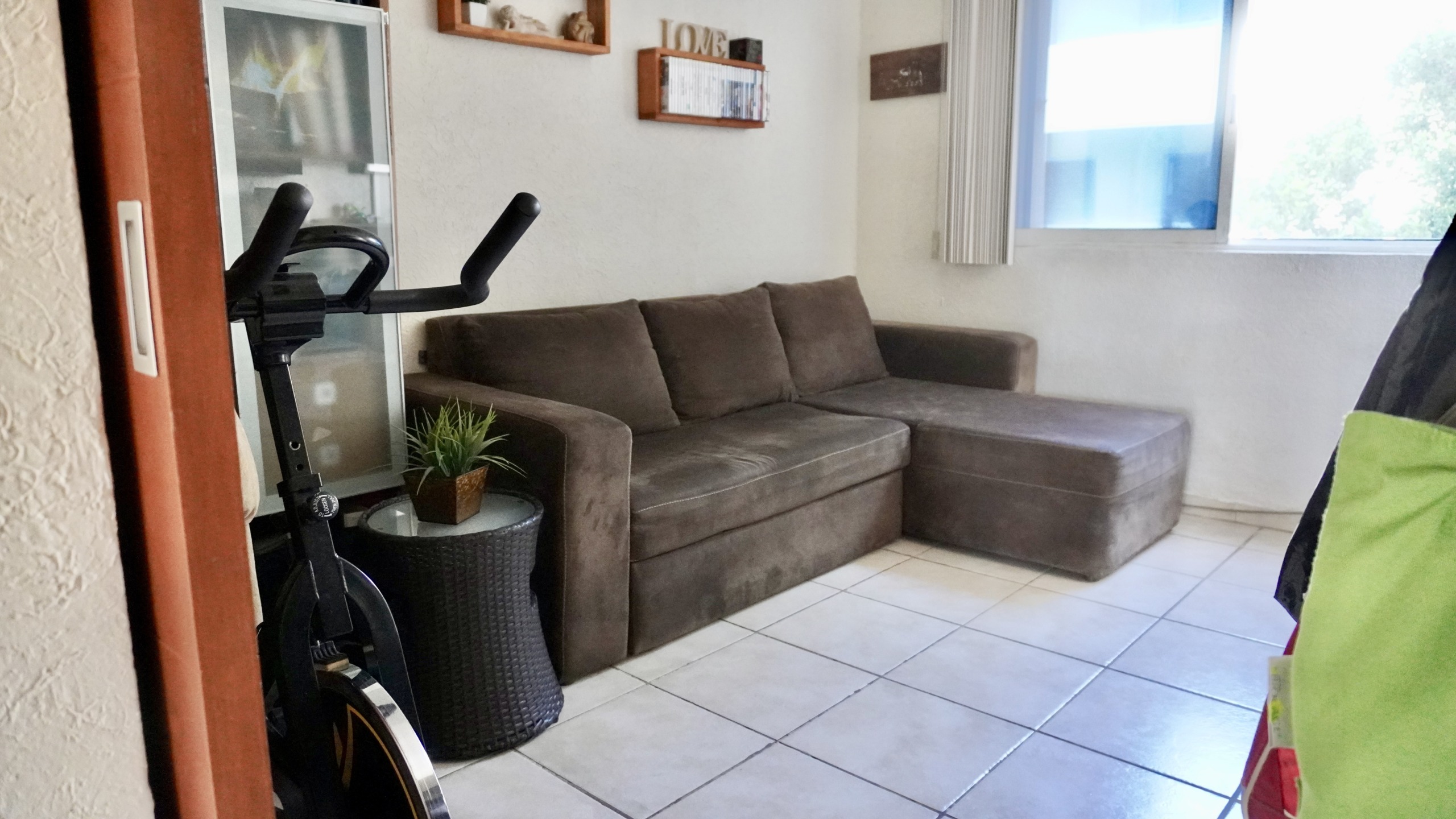 Departamento en venta en centro cancún - Sala de estar con sofá café. Ventana con vista al exterior