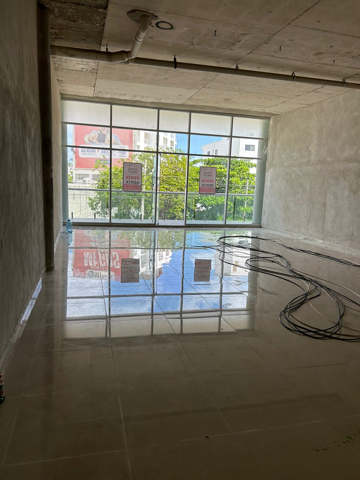 Local en venta o renta puerto cancún-Local con amplios ventanales de cristal, piso de loseta brillante y techo de concreto