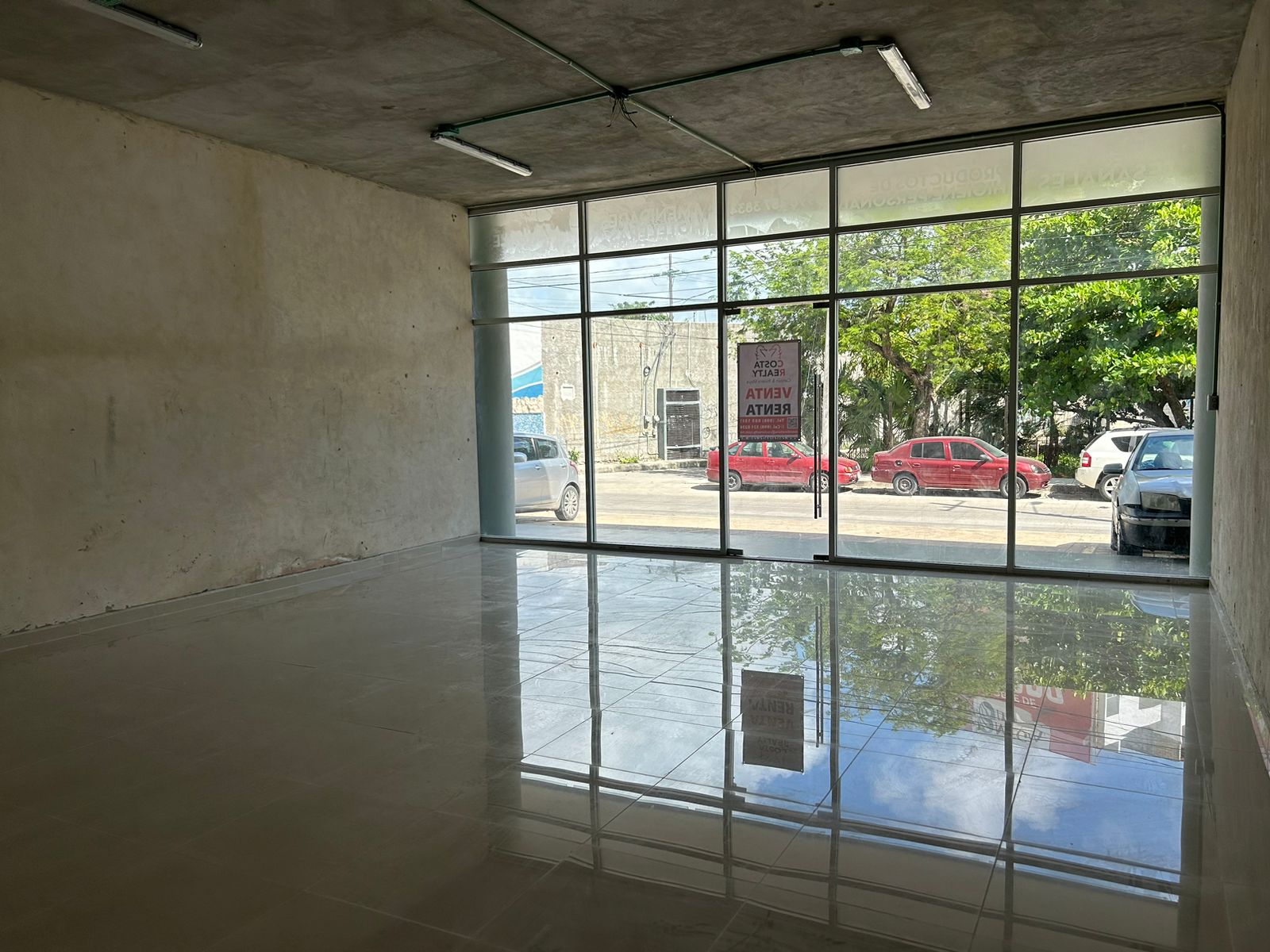 Local en venta o renta puerto cancún-Local con amplios ventanales de cristal, piso de loseta brillante y techo de concreto