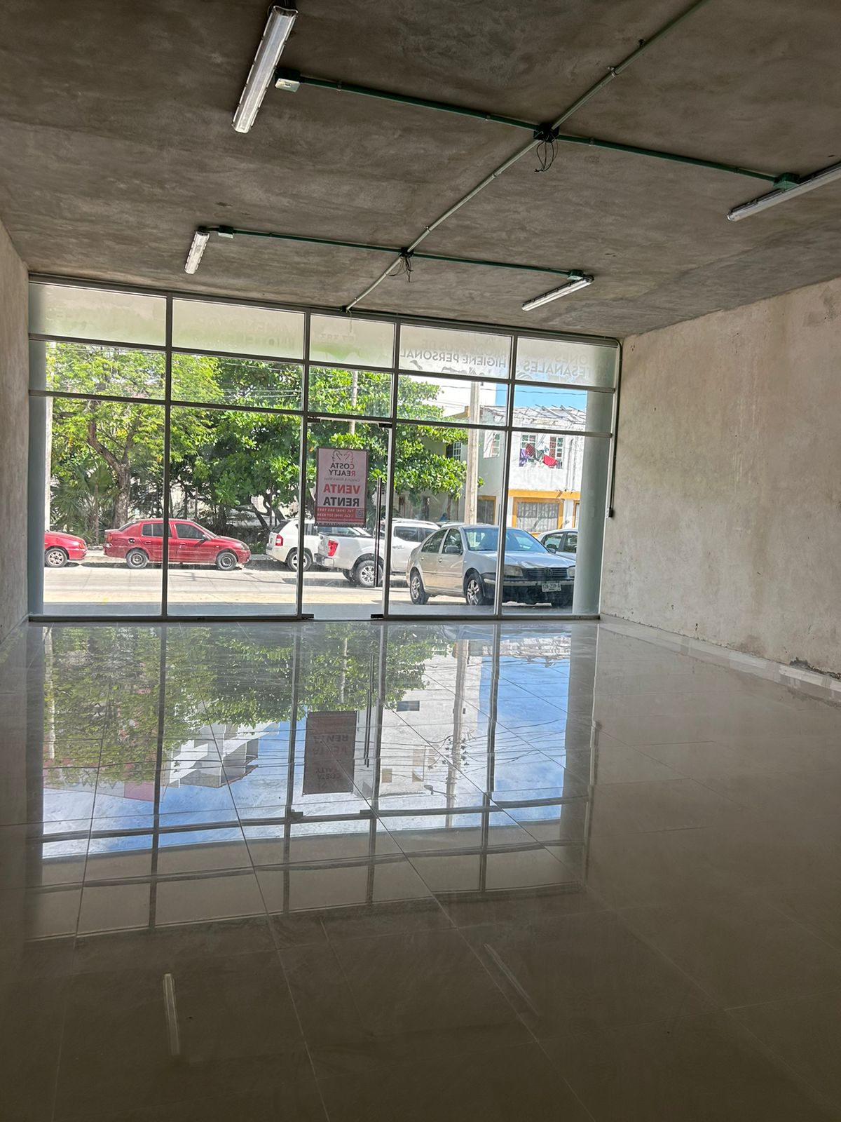 Local en venta o renta puerto cancún-Local con amplios ventanales de cristal, piso de loseta brillante y techo de concreto