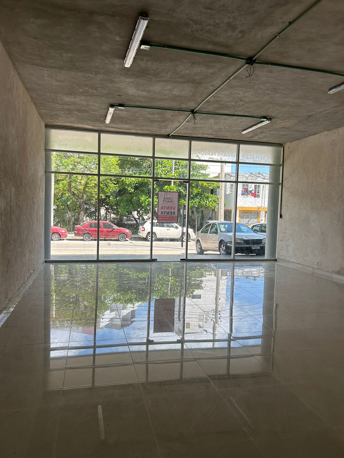 Local en venta o renta puerto cancún-Local con amplios ventanales de cristal, piso de loseta brillante y techo de concreto