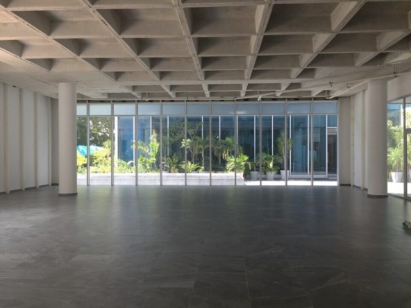 oficina en venta en cancún centro - local comercial amplio con piso de loseta gris, techos altos y ventanales de cristal que dan a un pasillo