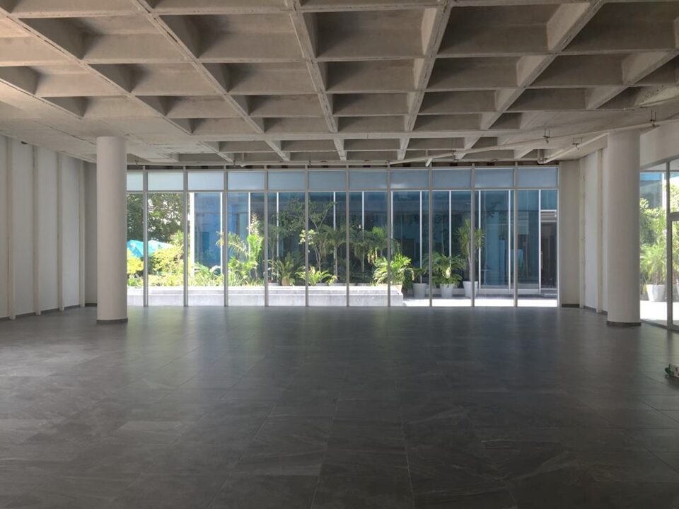 oficina en venta en cancún centro - local comercial amplio con piso de loseta gris, techos altos y ventanales de cristal que dan a un pasillo
