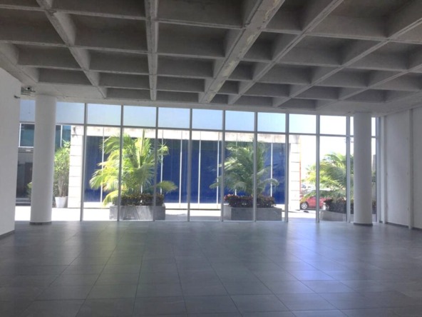 oficina en venta en cancún centro - local comercial amplio con piso de loseta gris, techos altos y ventanales de cristal que dan a un pasillo